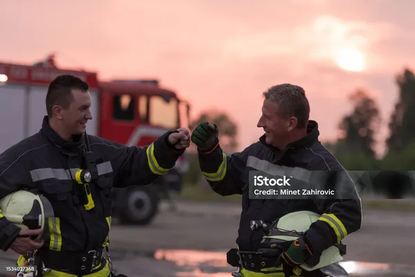 Viele Feuerwehr-Leute stehen vor einem großen roten Auto.